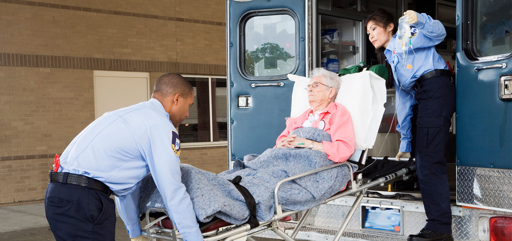 Two ambulance workers with senior woman
