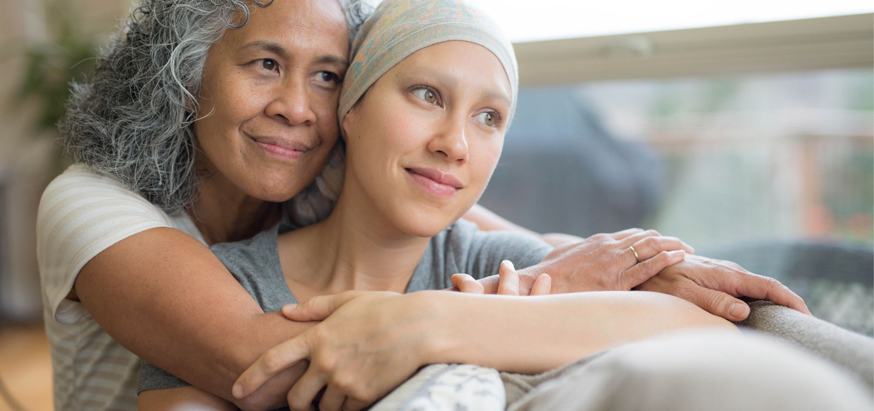 Senior woman hugging younger female cancer patient