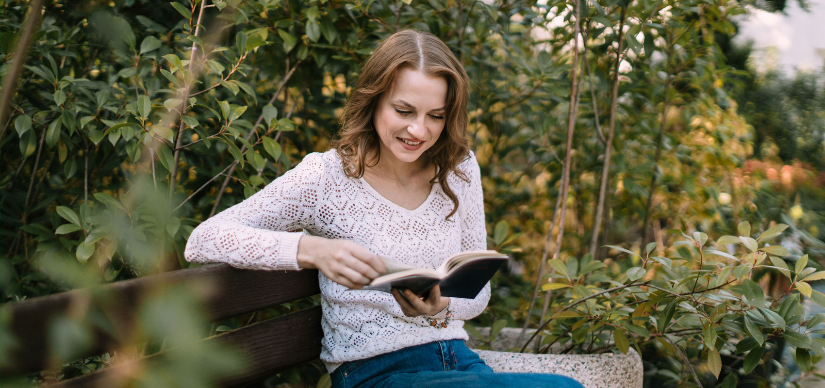 Woman reading her Bible on a bench in a garden