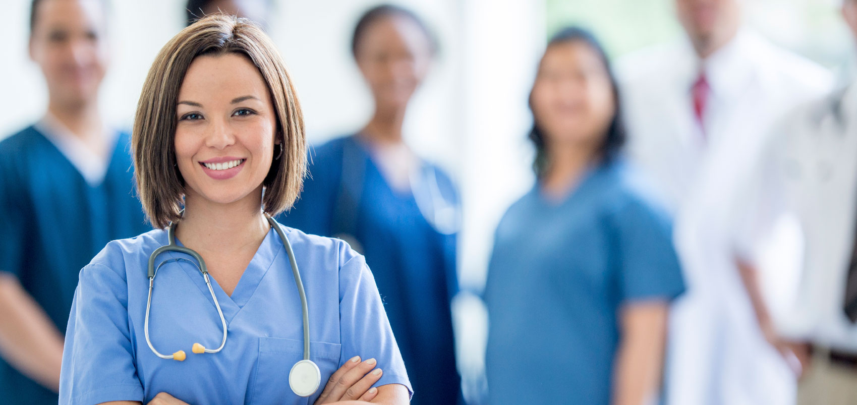 Female medical provider crossing arms while in front of a group of providers