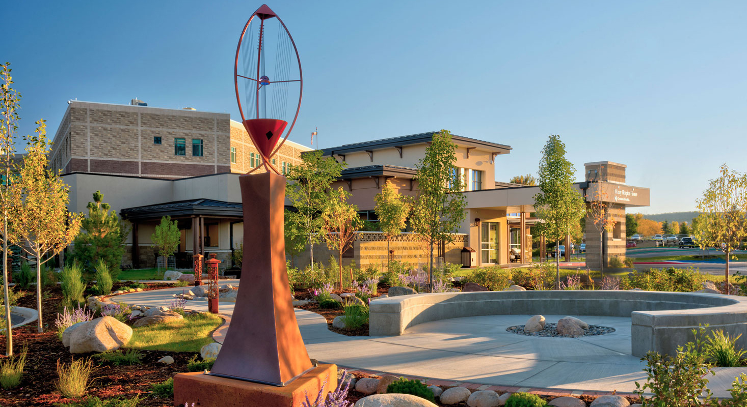 An exterior view of Hospice of Mercy showing gardens, walking paths, and public art