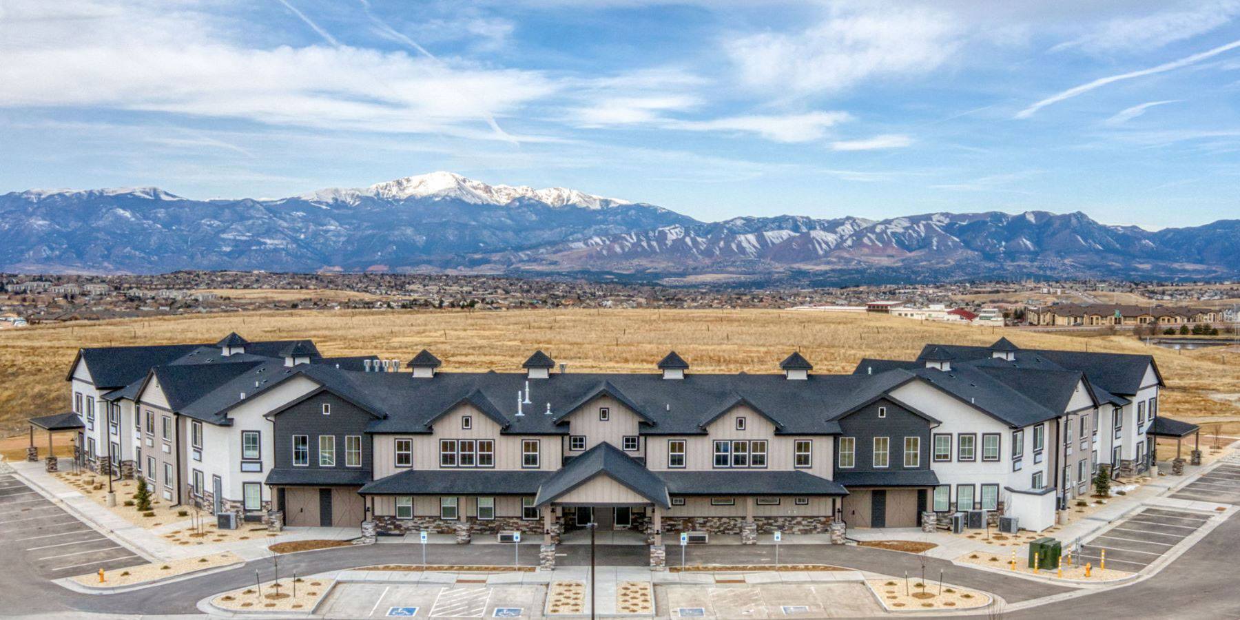 A view of the exterior of Ingram Guest House under a blue sky with a majestic view of the mountains