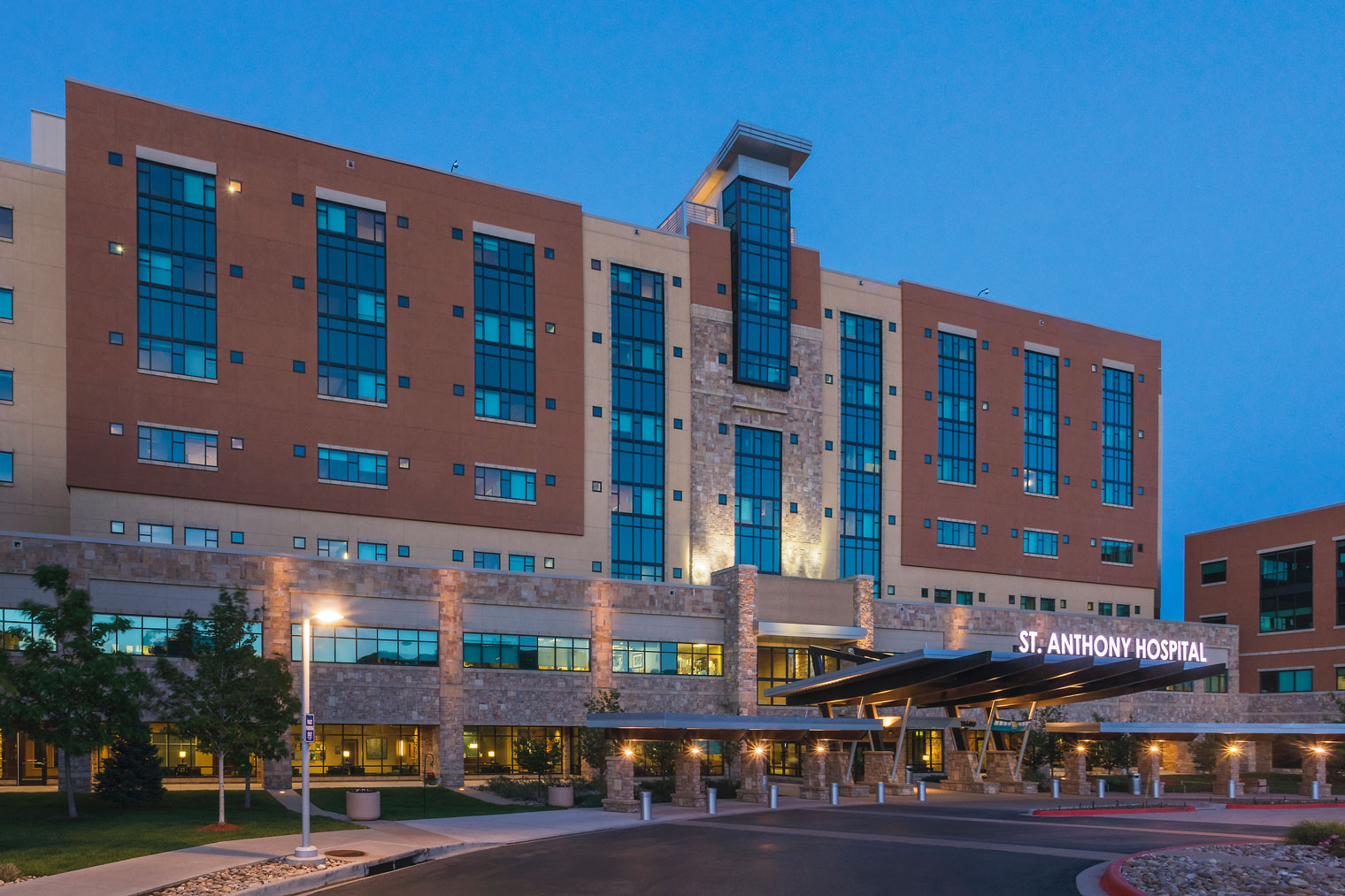 A view of the exterior of Saint Anthony hospital in the evening, lit against a deep blue sky