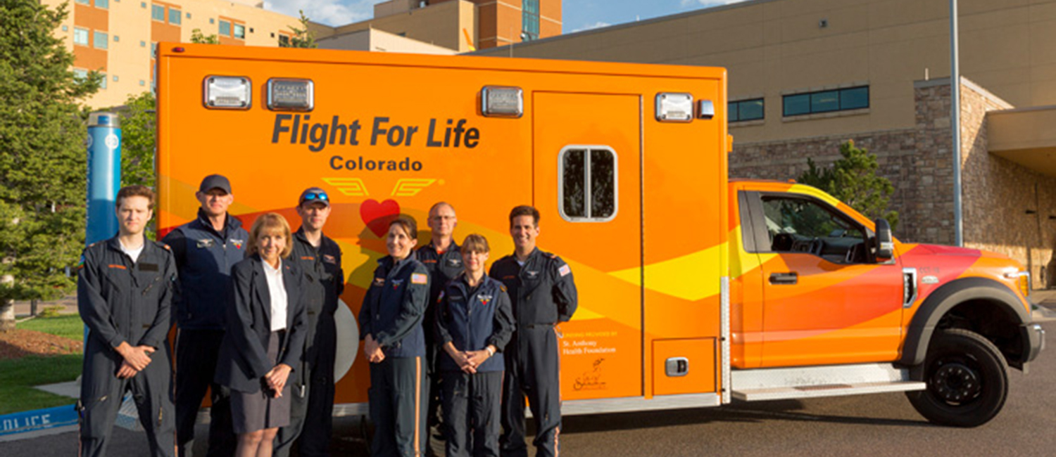 A trauma team poses before an orange flight for life ambulance