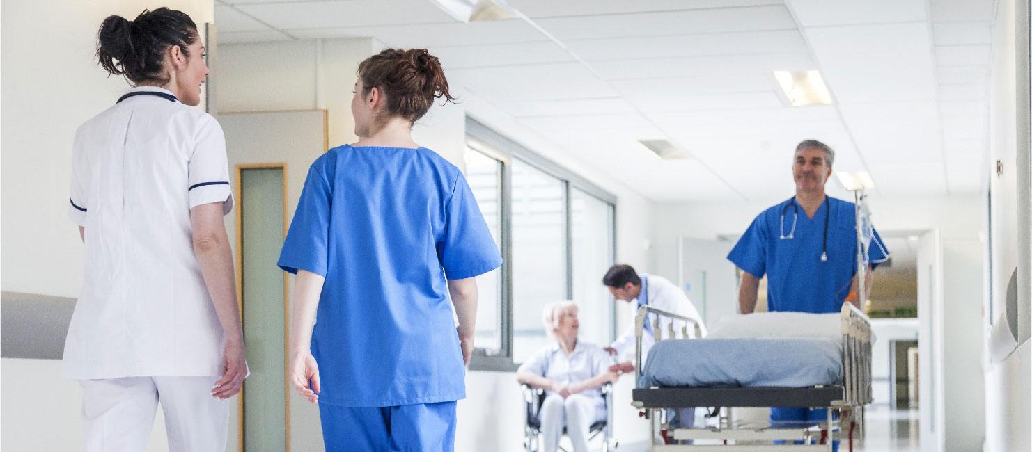 Nurses and other staff walk through a busy hospital corridor