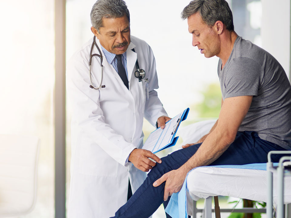 Male provider showing male patient where knee issue is located.