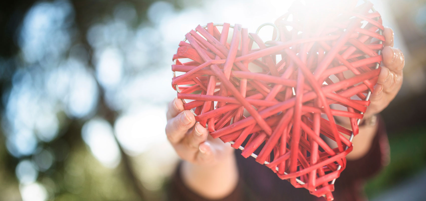 Woven heart being held by hands outside