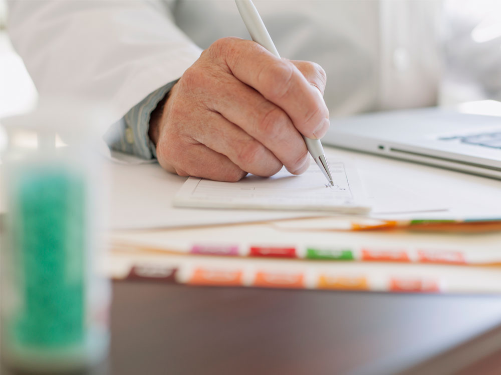 A hand writing notes in medical chart